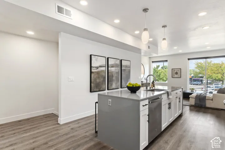 Central kitchen island with a stone-finish countertop, stainless steel sink, and pendant lighting Pictures are of the model home