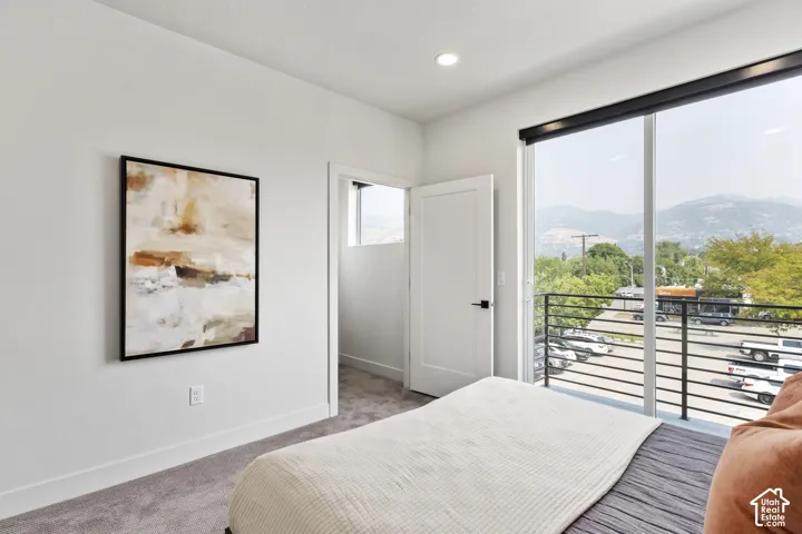 Spacious room with plush carpeting, recessed lighting, and a full-light door accessing a balcony with black metal railings Pictures are of the model home