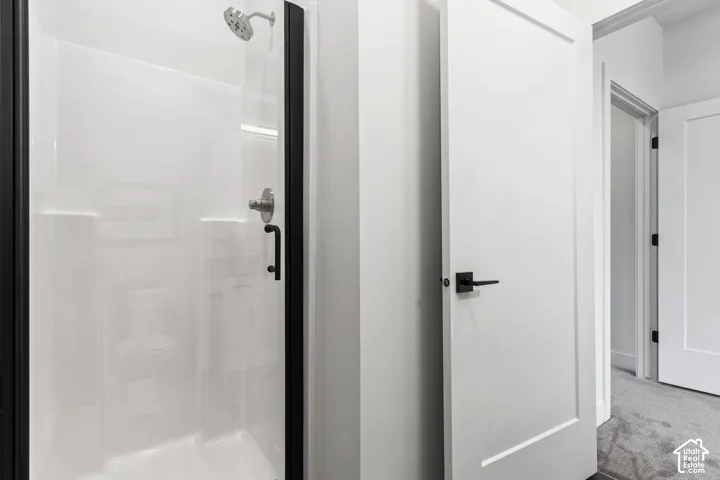 Walk-in shower with black-framed glass enclosure, brushed nickel showerhead, and a white integrated shower system