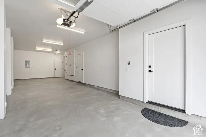 Spacious garage featuring a concrete floor, multiple entry doors, and overhead lighting