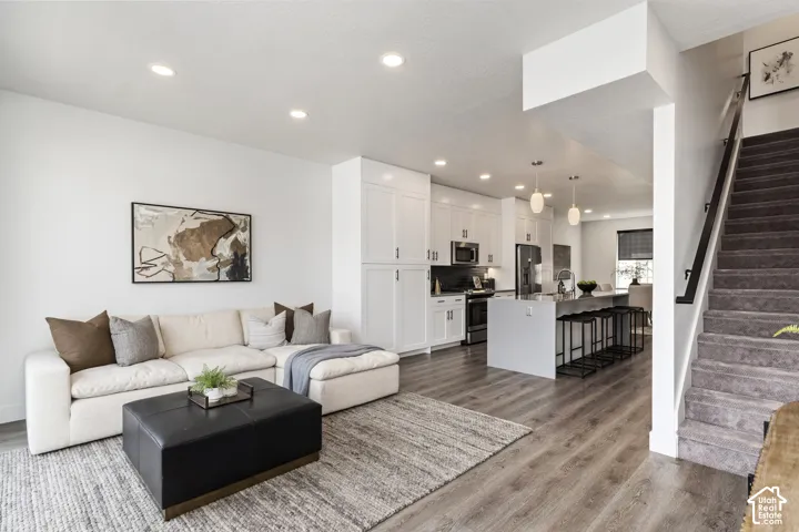 Open-concept living space featuring wood-finish flooring, recessed lighting, a modern kitchen with white cabinetry, and a central island with pendant lighting Pictures are of the model home