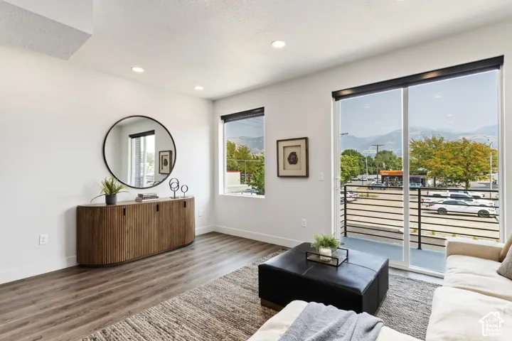 Recessed lighting, wood-finish flooring, sliding glass door, fixed windows, and a metal-railed balcony. Pictures are of the model home