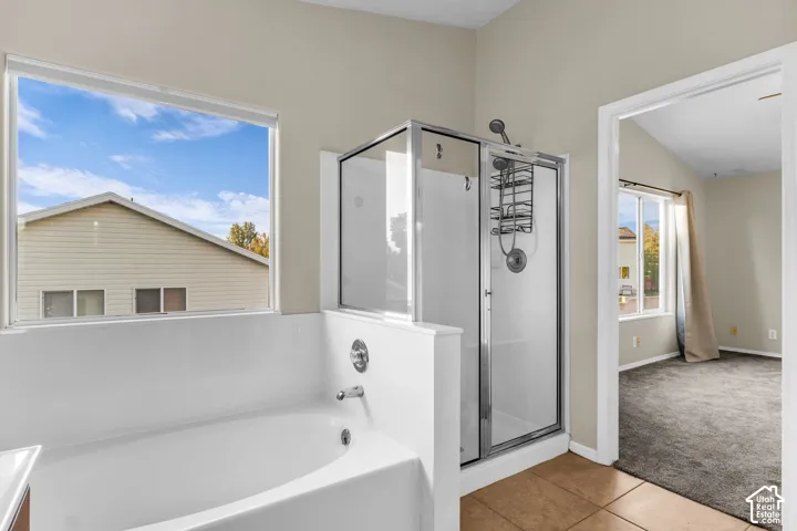 Built-in tub, enclosed glass shower, tiled flooring, and a large window