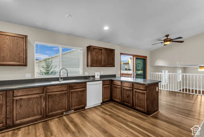 Wood finish cabinetry, solid surface countertops, recessed lighting, and a vaulted ceiling with a ceiling fan