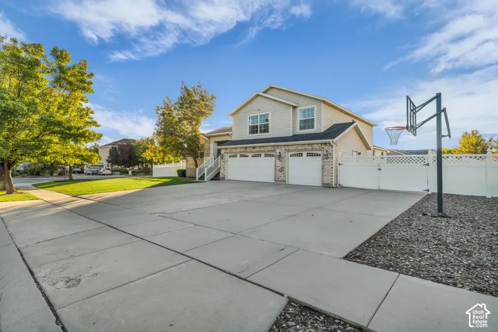 Three-car garage, light-toned siding, and a white privacy fence