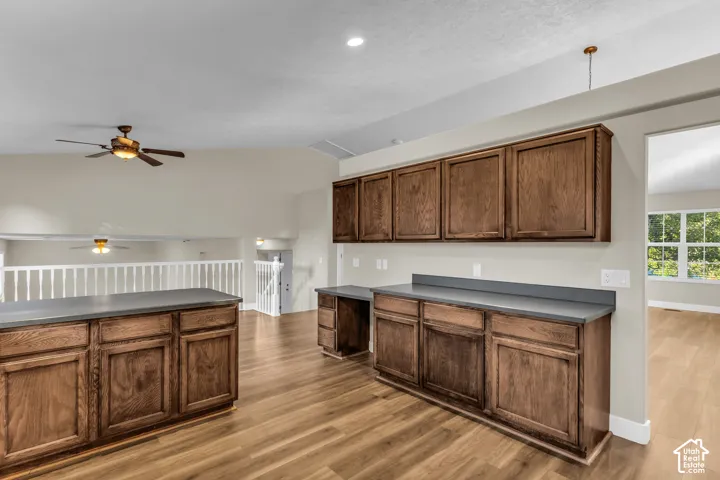 wood cabinetry, solid surface countertops, integrated ceiling fan, and an open to step down family room