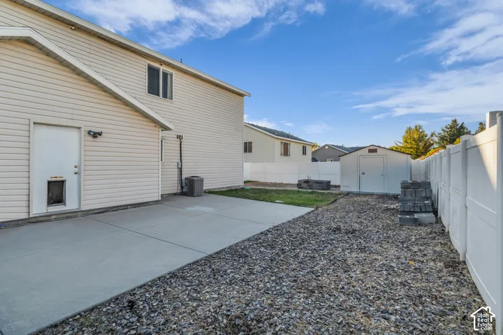 Concrete RV or toy parking with a white privacy fence, and a detached storage shed