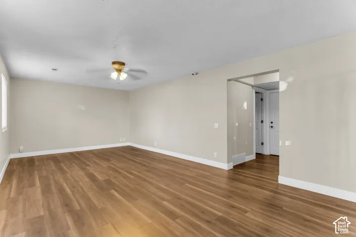 Spacious family room featuring LVP flooring, light-toned walls, a ceiling fan with integrated lighting, and white trim