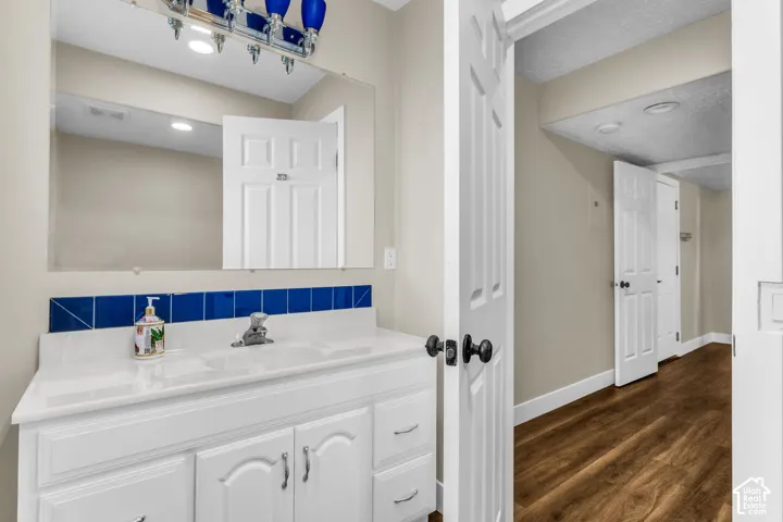 Main level half bath white vanity with undermount sink, chrome faucet, and blue tile backsplash
