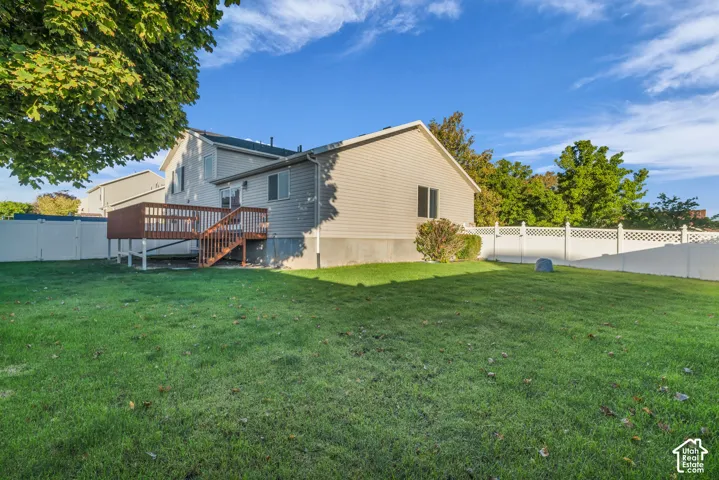 Expansive grassy yard featuring a multi-level wood deck with stairs, and white privacy fencing, Nice out door entertaining area