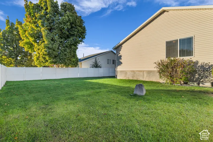 Expansive green space with a white privacy fence for fun yard games. fenced separate from garden area.
