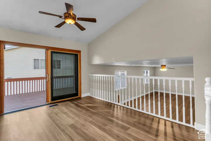 Vaulted ceiling with a ceiling fan, LVP flooring, sliding glass door with screen, access to large deck. white railing, open open to family room