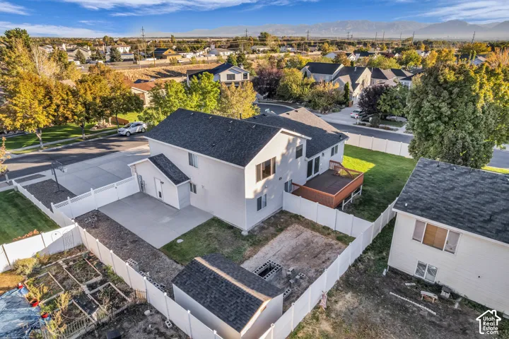 White vinyl fencing encompasses the property, featuring a concrete RV or toy parking area, a wooden deck, and a detached storage shed
