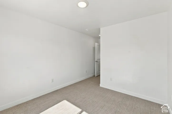 Carpeted flooring, white walls, white trim, recessed ceiling light, and a white door with a silver-tone knob