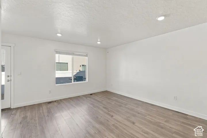 Recessed lighting, wood-finish flooring, white walls, and a large window with white trim