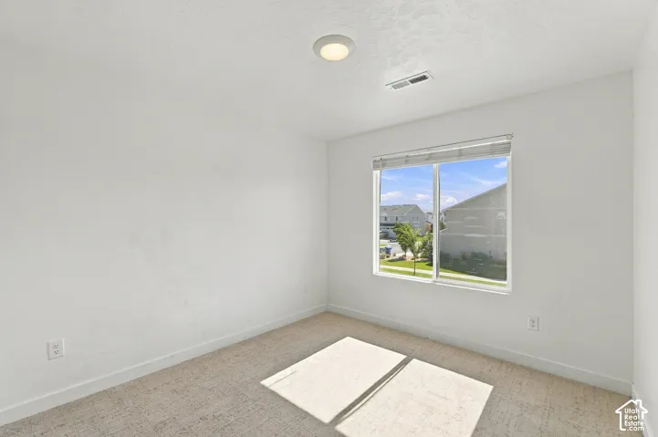 Recessed lighting, large window with blinds, light-colored carpet flooring, and white walls