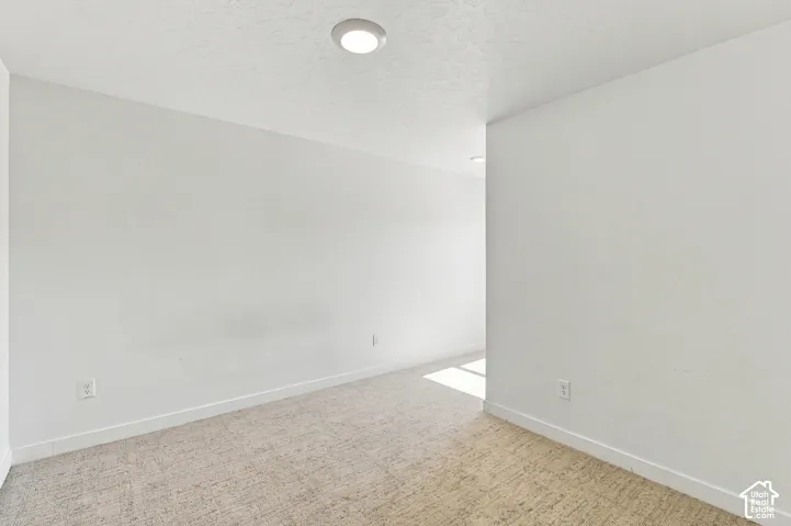 Recessed ceiling lighting illuminates a neutral color palette throughout this space, featuring light-toned carpet flooring and white walls