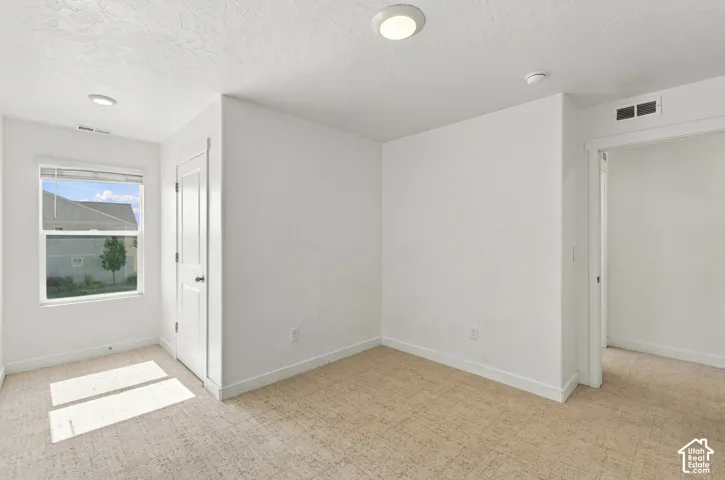 Carpeted room with white walls, a single window, and recessed lighting