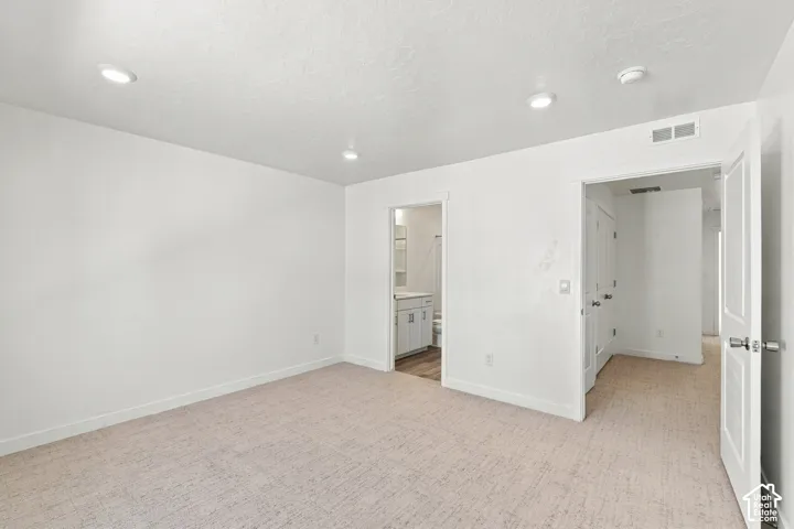 Recessed lighting, light-toned carpeting, and white painted walls