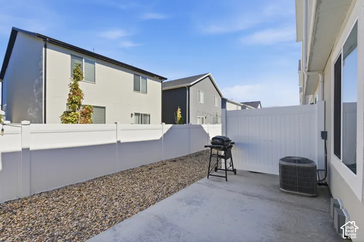 Concrete patio area with a white privacy fence, bordered by decorative gravel