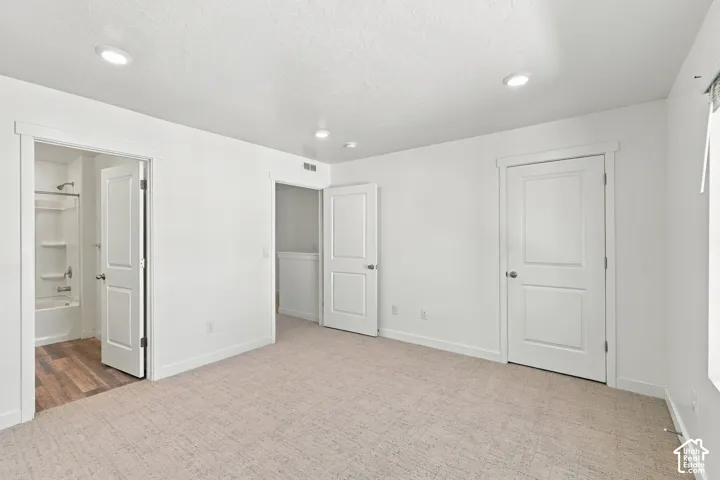 Neutral-toned carpeting, white walls, recessed lighting, and white paneled doors