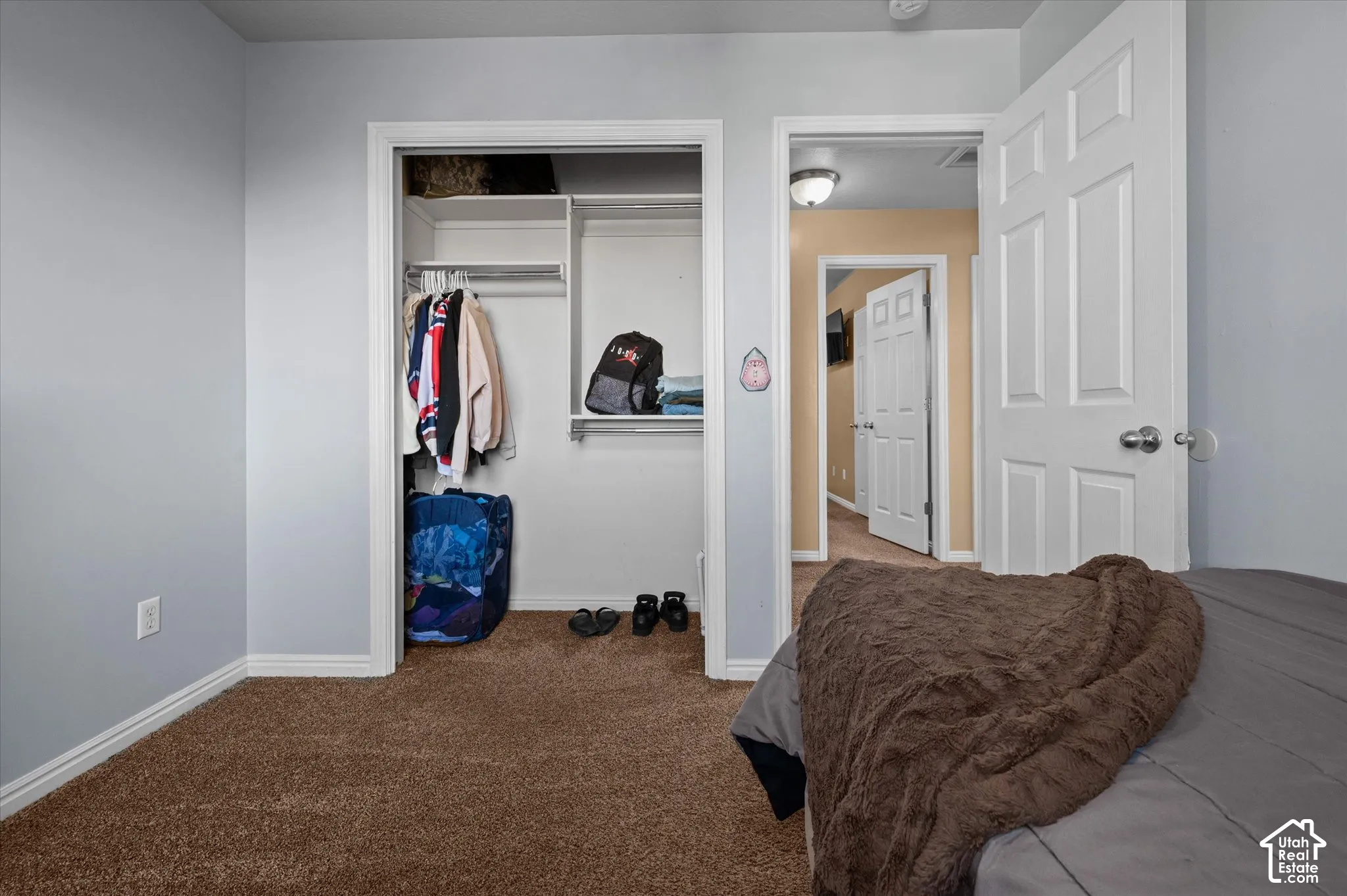 Wall-to-wall carpeting, light-toned wall paint, white trim, and a built-in closet with shelving