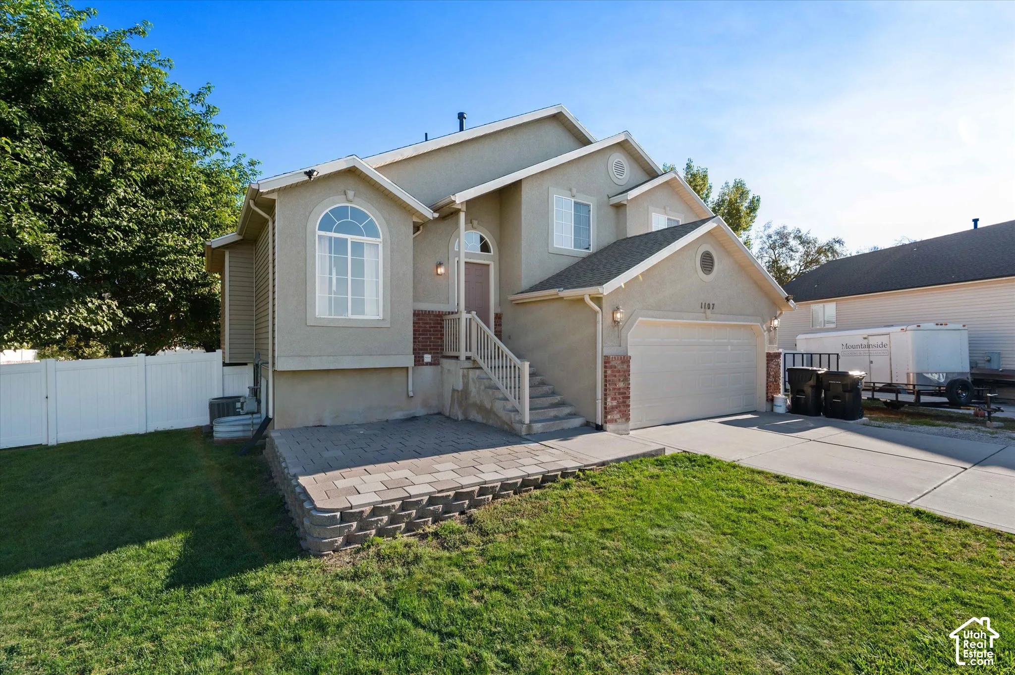 Stucco exterior with brick accents, arched windows, an attached garage, and a paver patio with a retaining wall