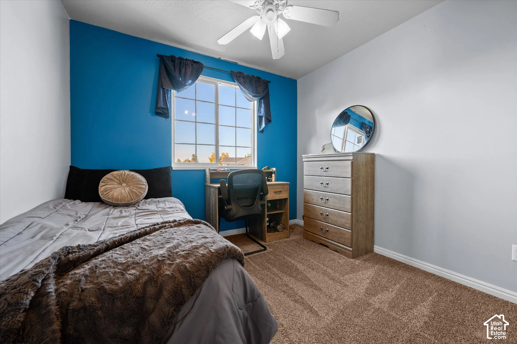 Carpeted flooring, ceiling fan, and a large window providing ambient light