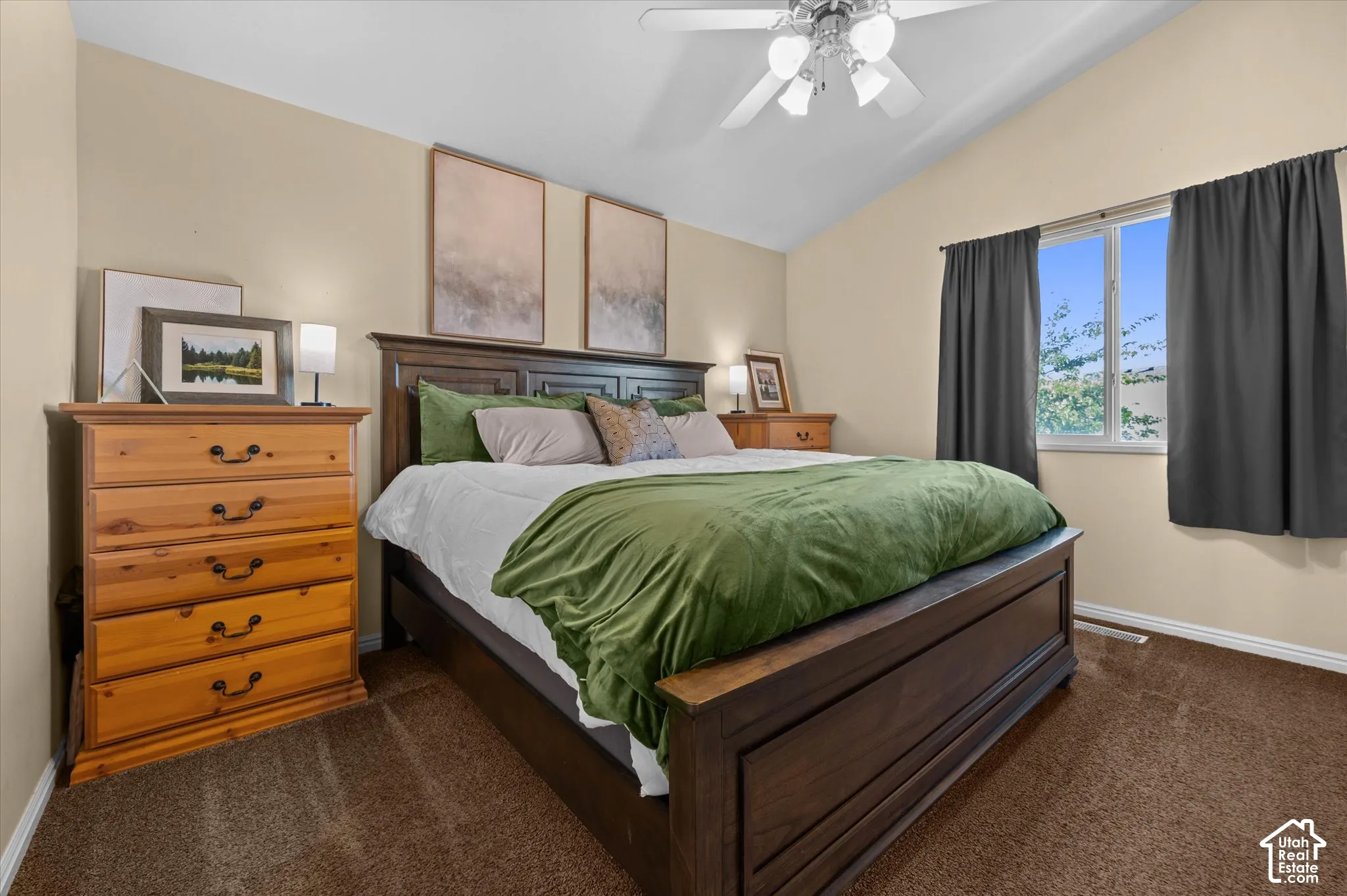 Vaulted ceiling with a ceiling fan, window with dark drapes, and brown carpet flooring