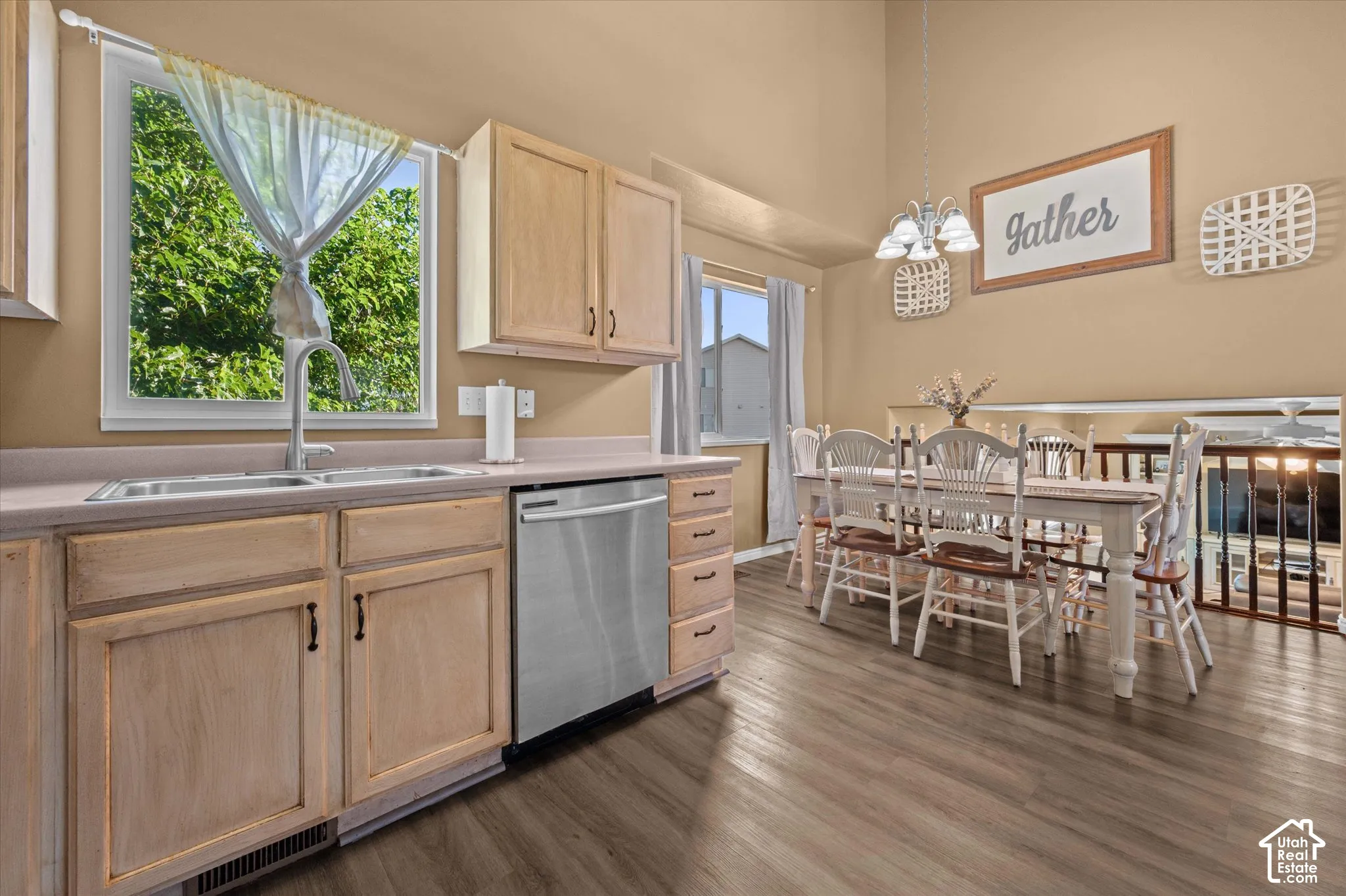 Kitchen with wood-finish flooring, light wood cabinetry, stainless steel dishwasher, and a double basin sink