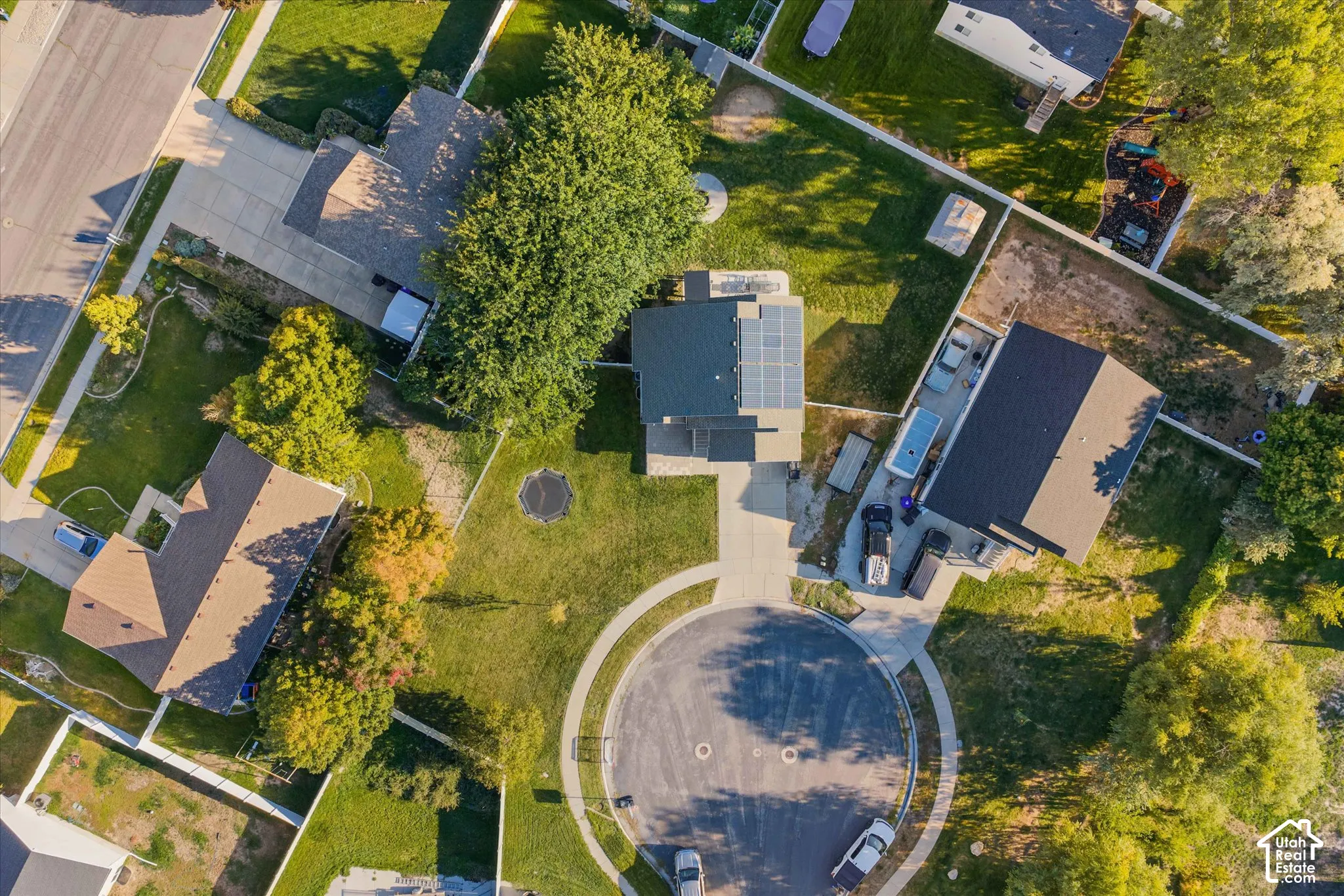 Property featuring a cul-de-sac location, paved driveways, a mature tree, and solar panels