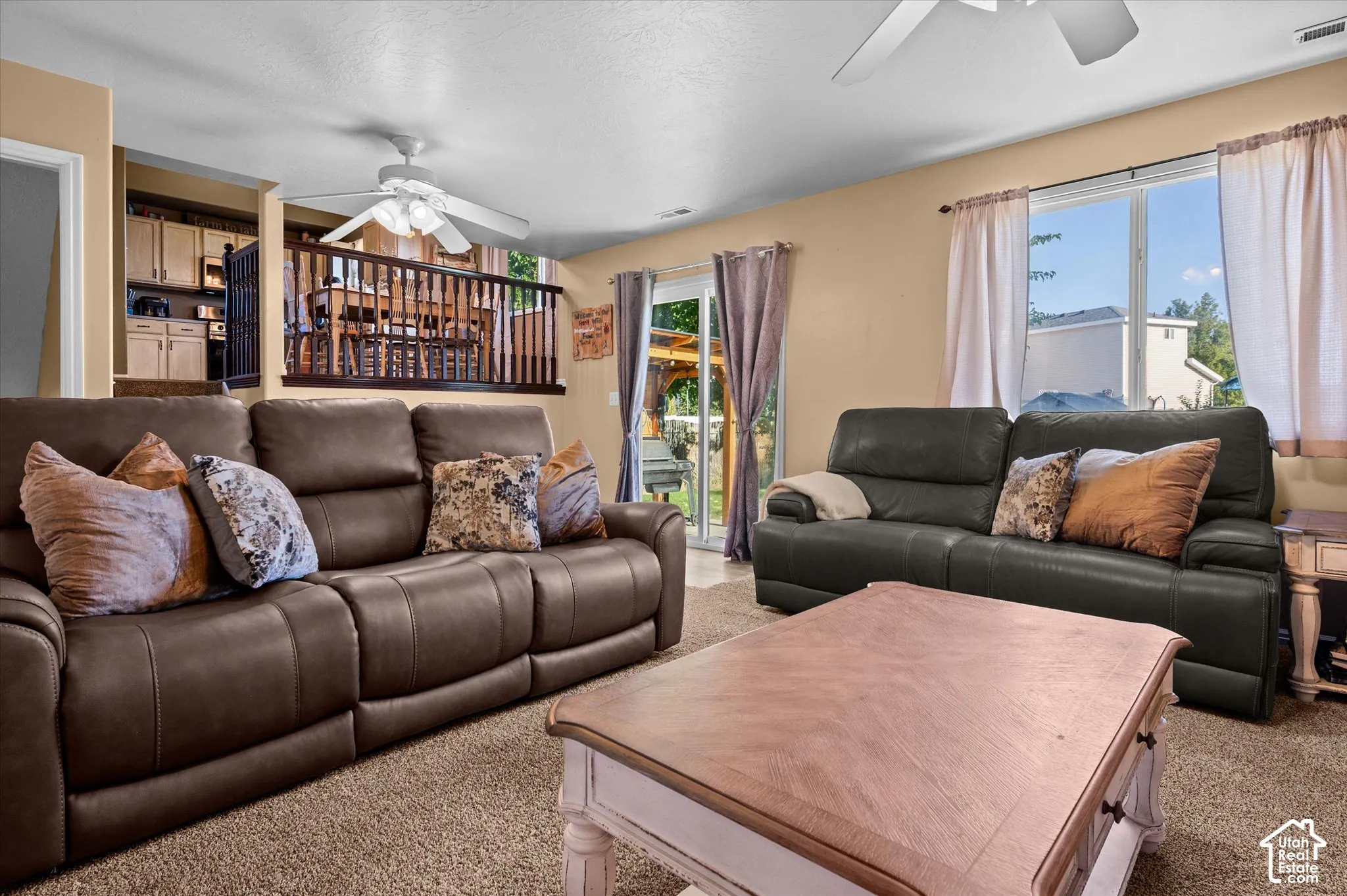 Open-concept living space featuring a sliding glass door, overhead ceiling fans, and a partial view of a kitchen area with cabinetry