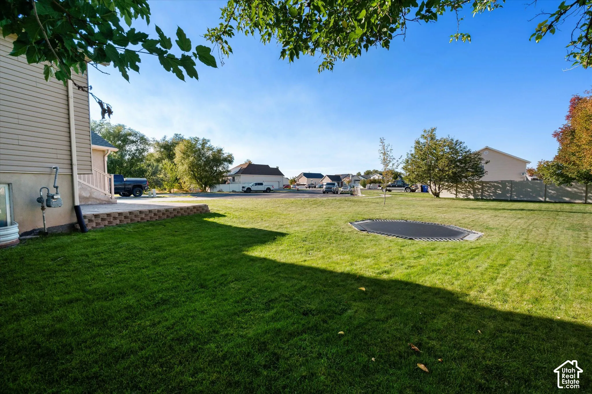 Expansive lawn with a built-in trampoline, mature trees, and a retaining wall