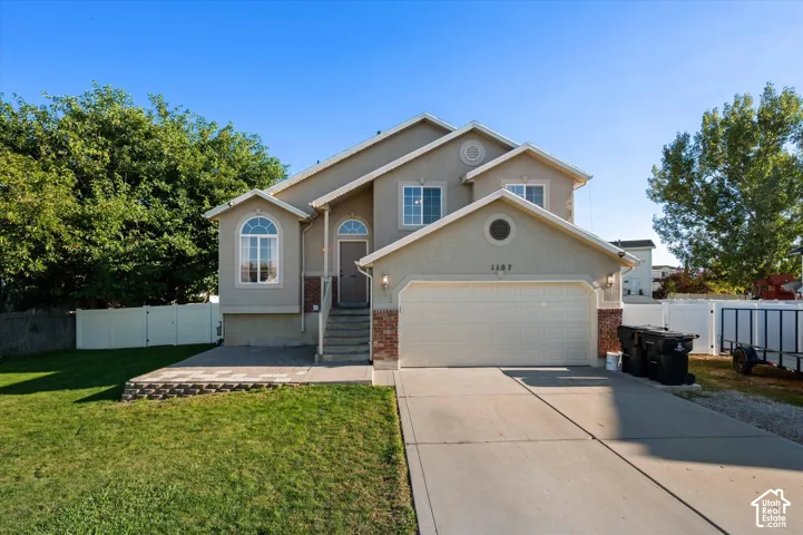 Stucco exterior with brick accents, arched windows, attached two-car garage, concrete driveway, and front lawn