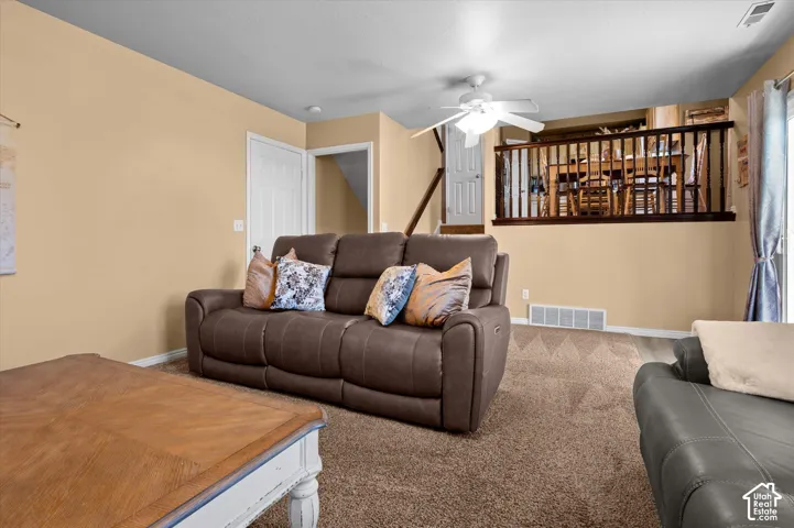 Carpeted flooring, ceiling fan, white paneled doors, wood railing, and sliding glass door