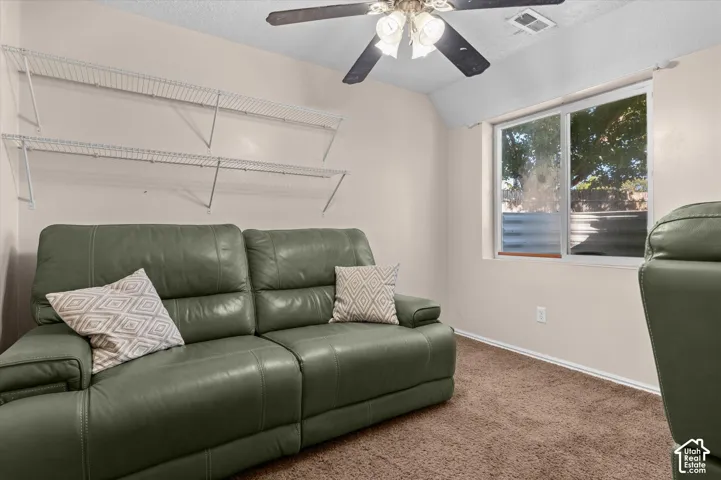 Carpeted flooring, white wire shelving, light-colored walls, ceiling fan with integrated lighting, and a window