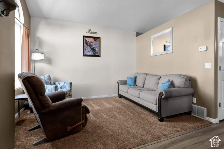 Wall-to-wall carpeting, wood-finish flooring, and a window with blinds