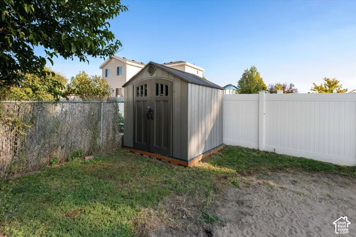 Detached storage shed featuring arched double doors, a gabled roof, and panel siding