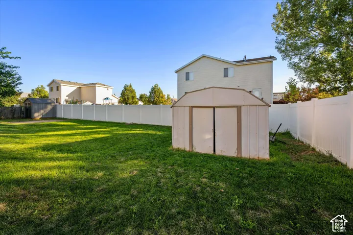 Expansive green lawn with a white privacy fence and two storage sheds