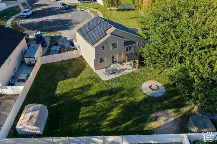 Rear exterior with solar panel array, attached covered patio, concrete patio, and a fire pit