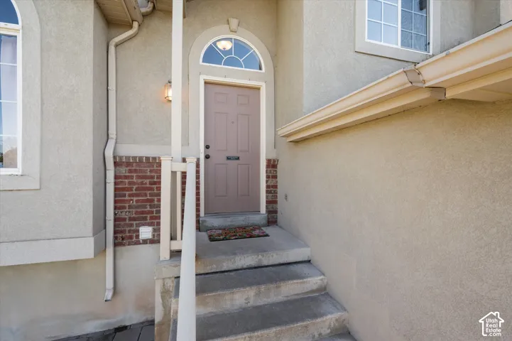 Stucco exterior featuring a covered entry, arched transom window, and brick detailing