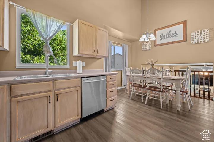 Kitchen with wood-finish flooring, light wood cabinetry, stainless steel dishwasher, and a double basin sink