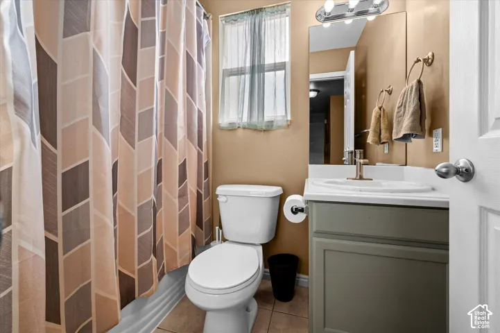 Bathroom featuring a single-sink vanity with a light countertop, a wall-mounted mirror, and a window for natural light