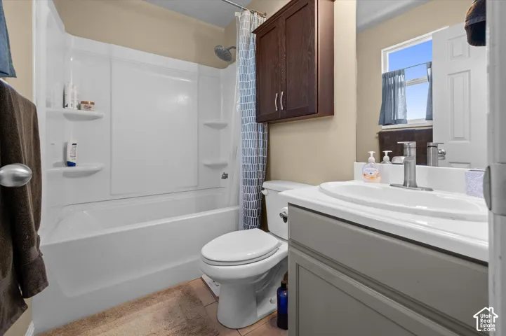 White bathtub with integrated shelving, brushed nickel shower head, single basin vanity with brushed nickel faucet, and wood-finish wall-mounted cabinetry