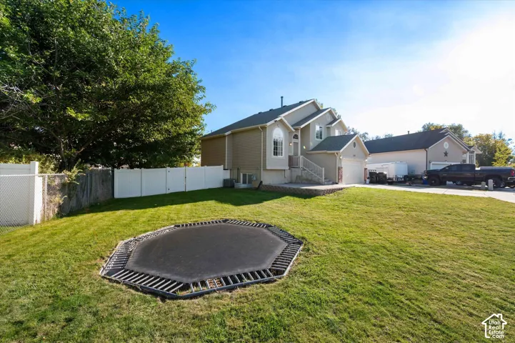 Expansive sloped lawn with mature trees and a white privacy fence