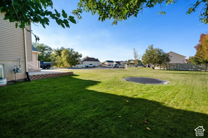 Expansive lawn with a built-in trampoline, mature trees, and a retaining wall