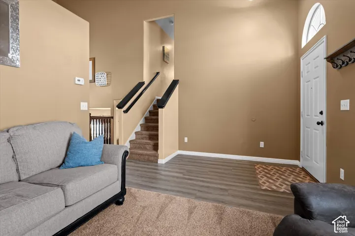 Entryway with vaulted ceiling, arched transom window, wood-finish flooring, and carpeted stairs with black handrails