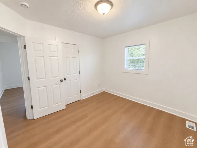 Wood-finish flooring, white paneled doors, recessed window, and flush-mount ceiling light