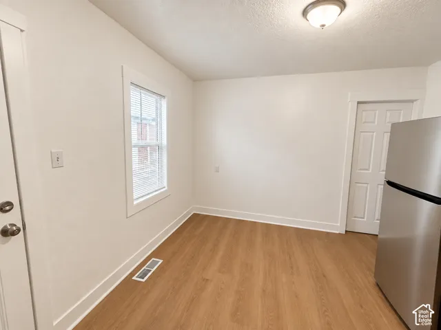 Wood-finish flooring, white trim, and a window with blinds