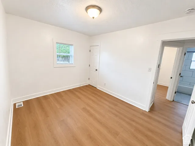 Wood-finish flooring, white walls, single window, flush mount ceiling light fixture, white trim